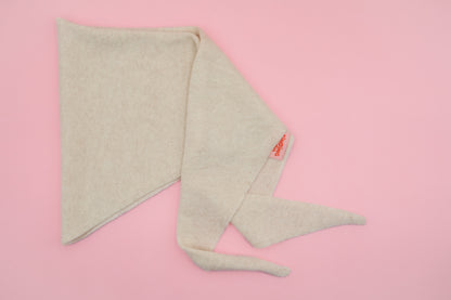 Beiges Finding Dodo Dreiecktuch aus 100% Kaschmir in der Farbe Pearl auf rosa Hintergrund.