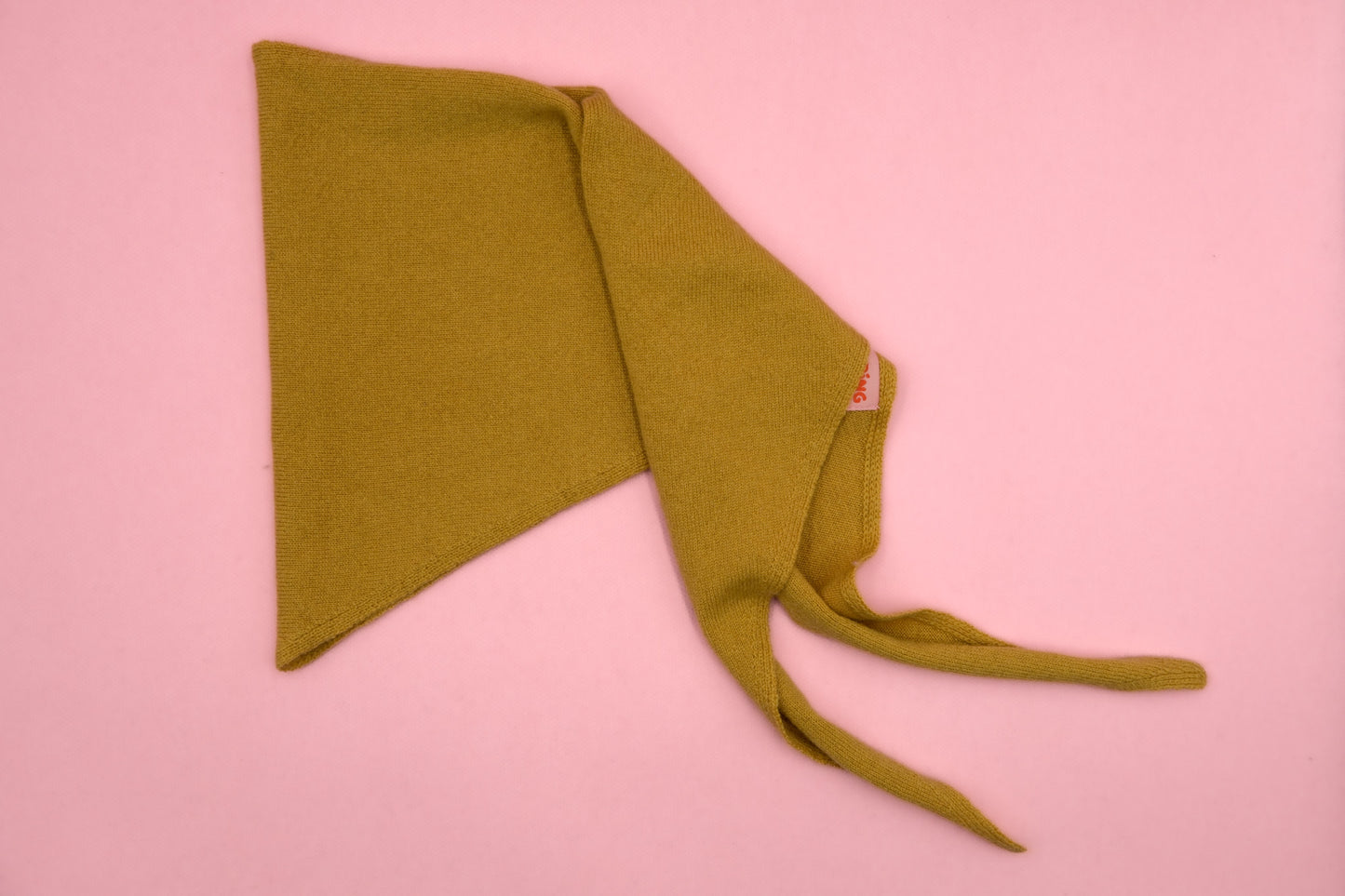 Mustard senfgelbes Finding Dodo Dreiecktuch aus 100% Kaschmir auf rosa Hintergrund.