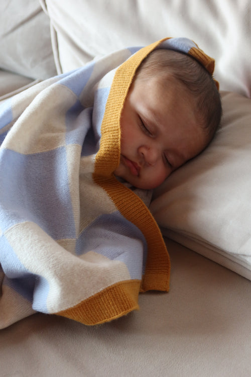 Schlafendes Baby eingewickelt in einer blau-beige karierten Kaschmirdecke von Finding Dodo.